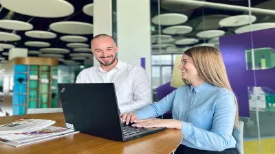 Ein vielfältiges Team von Mitarbeitern posiert zusammen in einem Besprechungsraum voller Post-its und hat Spaß.
