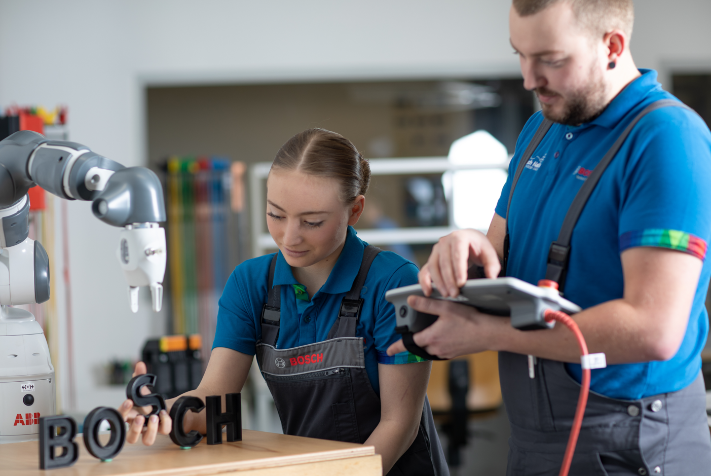 Eine Mitarbeiterin posiert vor einem Regal voller Mützen mit Bosch-bezogenen Prints wie z.B. Work #LikeABosch.