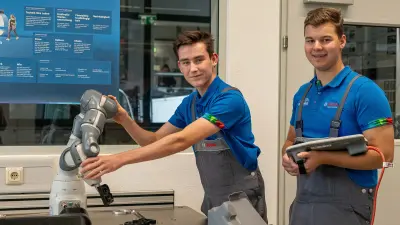 Zwei junge Männer mit einem blauen Bosch-Polohemd und Mundschutz stehen vor einem Bosch-Plakat.
