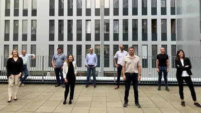 Kolleginnen und Kollegen stehen mit Abstand zusammen auf einer Dachterrasse