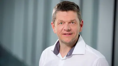 Ein Mann mit weißem Hemd lächelt in die Kamera
