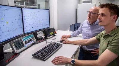 Zwei Techniker von Bosch Linz überwachen den PEM-Elektrolyse-Stack-Prüfstand über Steuerungsbildschirm