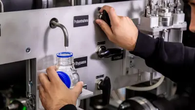 Techniker entnimmt Probe von deionisiertem Wasser an einer Anlage zur Analyse der PEM-Elektrolyse-Stack-Qualität