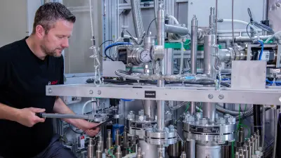 Bosch Techniker bereitet PEM-Elektrolyse-Stack am Teststand vor, Schrauben festziehend, für Leistungsprüfungen