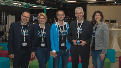 5 Personen tragen ein Event-Shirt und stehen zusammen.